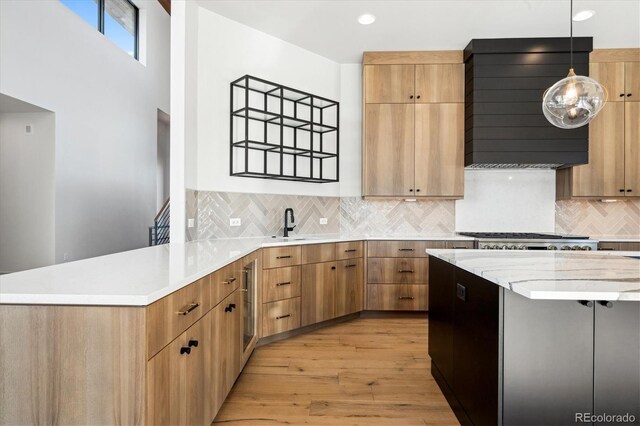 kitchen featuring backsplash, ventilation hood, light hardwood / wood-style flooring, decorative light fixtures, and kitchen peninsula