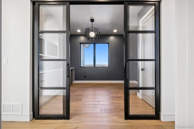 doorway to outside with hardwood / wood-style floors and a notable chandelier