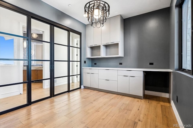 kitchen with white cabinetry, plenty of natural light, hanging light fixtures, and light hardwood / wood-style flooring