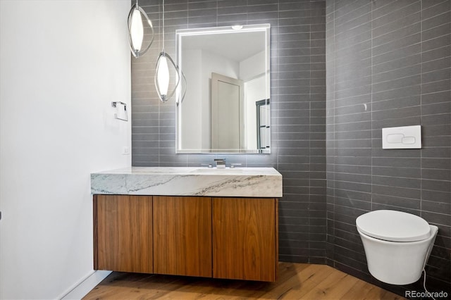 bathroom featuring vanity, toilet, wood-type flooring, and tile walls