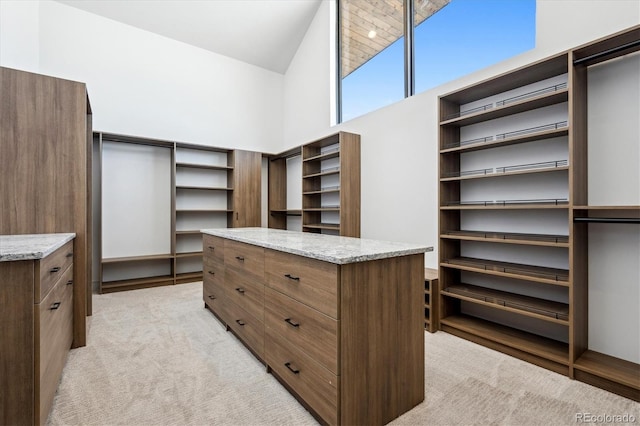 spacious closet featuring light colored carpet and high vaulted ceiling