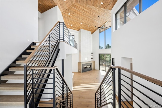 staircase with hardwood / wood-style floors, high vaulted ceiling, and wooden ceiling