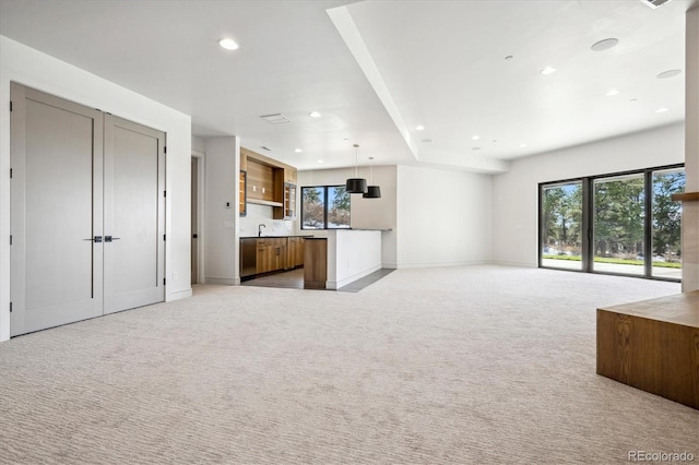 unfurnished living room featuring light carpet and sink