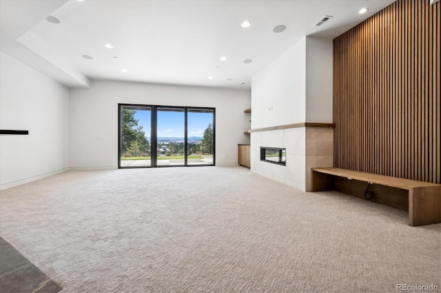 unfurnished living room with a tile fireplace and light colored carpet