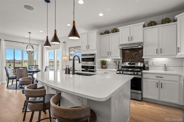 13410 New Ranch Dr, Peyton, CO 80831 - kitchen with appliances with stainless steel finishes, a sink, under cabinet range hood, recessed lighting, and tasteful backsplash