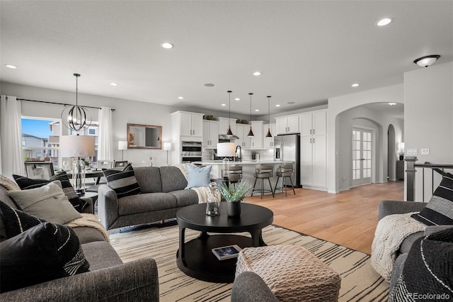 13410 New Ranch Dr, Peyton, CO 80831 - living area with arched walkways, plenty of natural light, light wood-style flooring, a chandelier, and recessed lighting