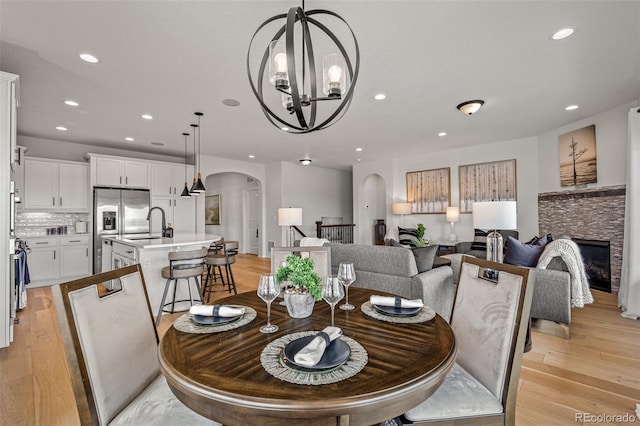 13410 New Ranch Dr, Peyton, CO 80831 - dining space with arched walkways, light wood-style floors, a chandelier, recessed lighting, and a fireplace
