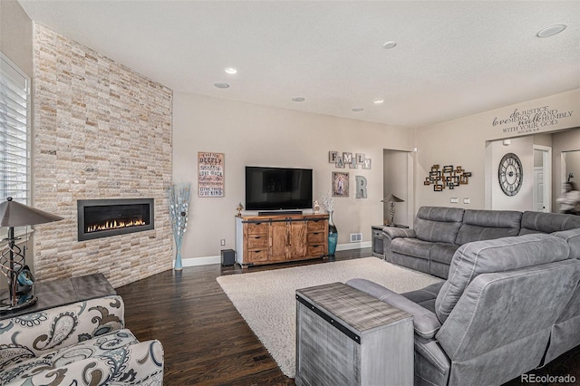 living room with dark wood-type flooring, a fireplace, and a textured ceiling