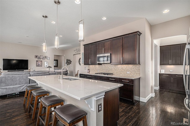 kitchen featuring sink, a breakfast bar area, hanging light fixtures, an island with sink, and stainless steel appliances