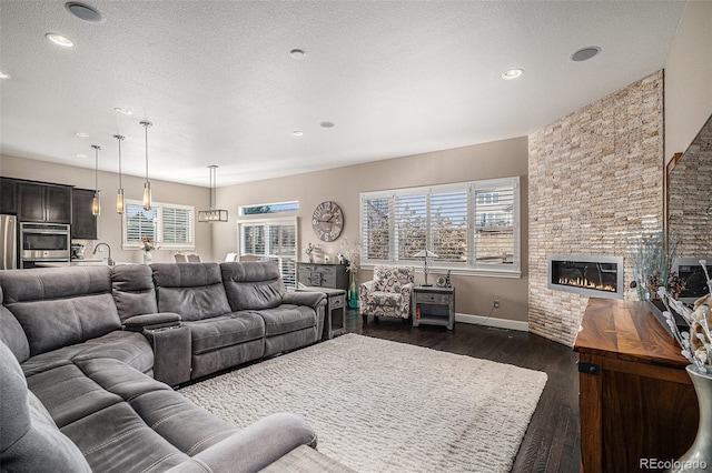 living room featuring a fireplace, dark hardwood / wood-style flooring, sink, and a textured ceiling