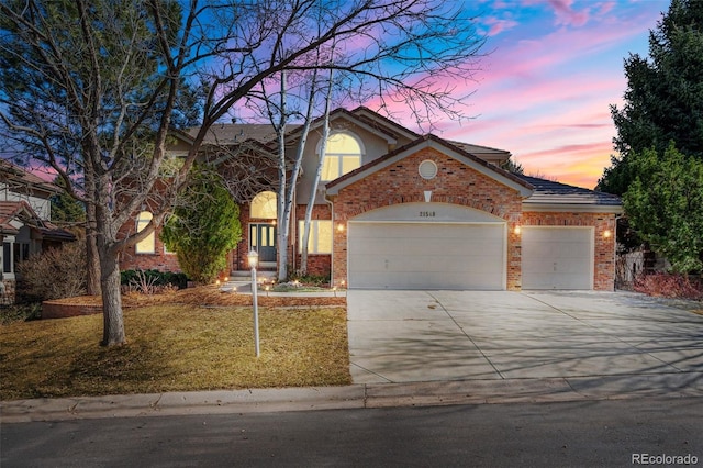 view of front of house featuring brick siding, an attached garage, driveway, and a front yard