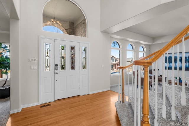 foyer featuring visible vents, baseboards, stairs, an inviting chandelier, and wood finished floors