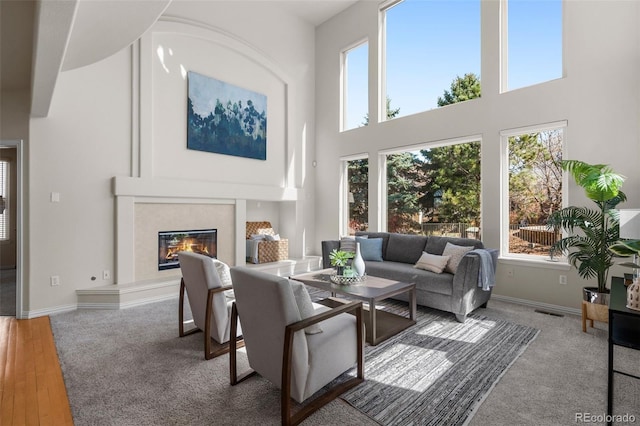 living area with a high ceiling, plenty of natural light, a fireplace, and visible vents