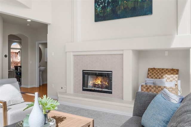 living area featuring baseboards, arched walkways, and a fireplace