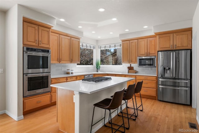 kitchen featuring light wood-type flooring, tasteful backsplash, visible vents, and stainless steel appliances