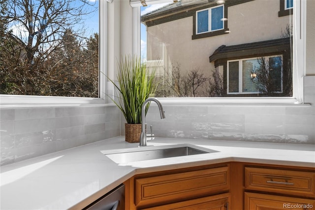 interior space with brown cabinetry, tasteful backsplash, light countertops, and a sink