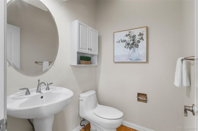 bathroom featuring toilet, baseboards, and a sink