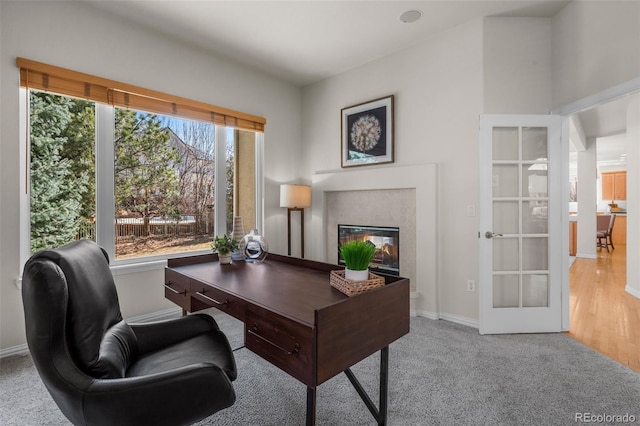 carpeted office space featuring a multi sided fireplace, french doors, and baseboards