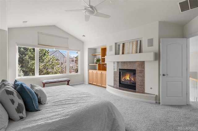 carpeted bedroom with visible vents, lofted ceiling, a ceiling fan, and a tiled fireplace