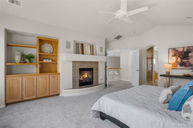 bedroom with vaulted ceiling, arched walkways, visible vents, and light carpet