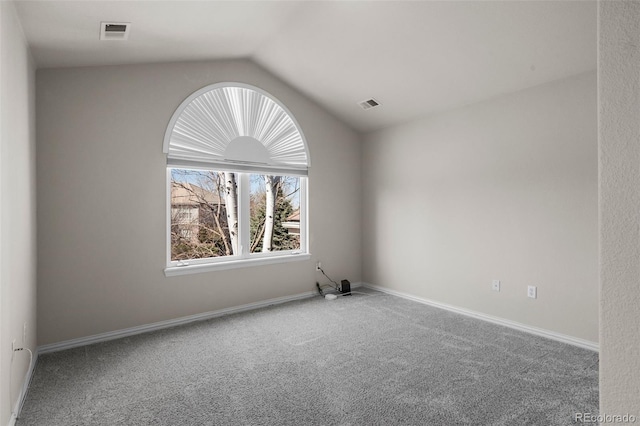 empty room featuring visible vents, baseboards, lofted ceiling, and carpet