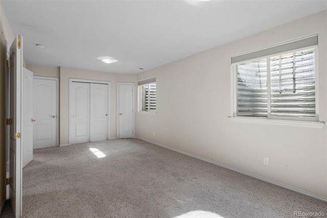 unfurnished bedroom with baseboards, two closets, and carpet