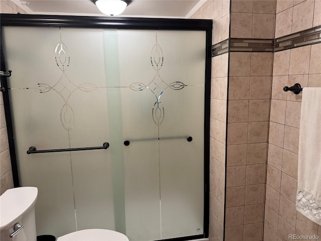 bathroom featuring toilet and a shower with shower door