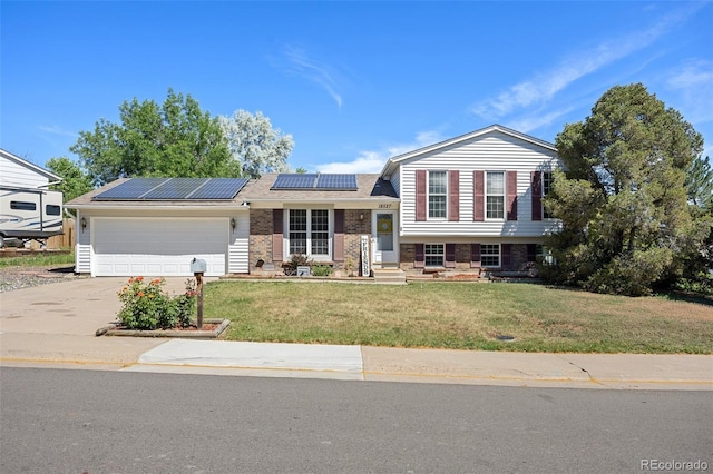 18527 E Kansas Pl, Aurora, CO 80017 - tri-level home with a garage, concrete driveway, a front lawn, solar panels, and brick siding