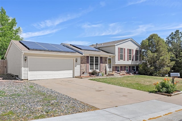 18527 E Kansas Pl, Aurora, CO 80017 - tri-level home with an attached garage, roof mounted solar panels, concrete driveway, and brick siding