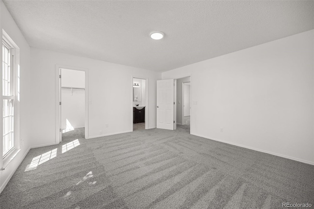 18527 E Kansas Pl, Aurora, CO 80017 - unfurnished bedroom featuring carpet, a textured ceiling, a spacious closet, ensuite bath, and a closet