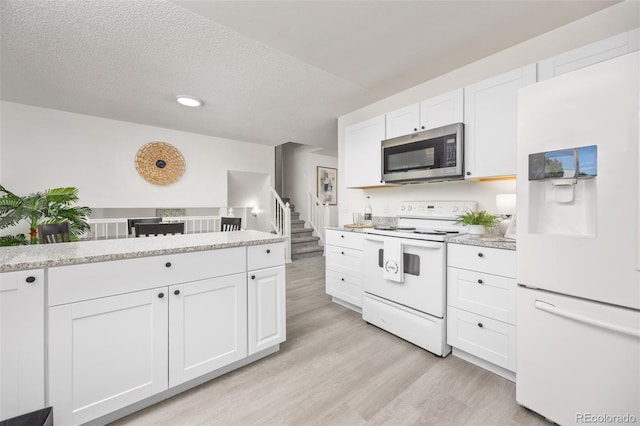18527 E Kansas Pl, Aurora, CO 80017 - kitchen with white appliances, light wood finished floors, white cabinetry, a textured ceiling, and light stone counters