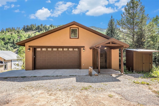 view of front facade featuring an outbuilding, an attached garage, and stucco siding