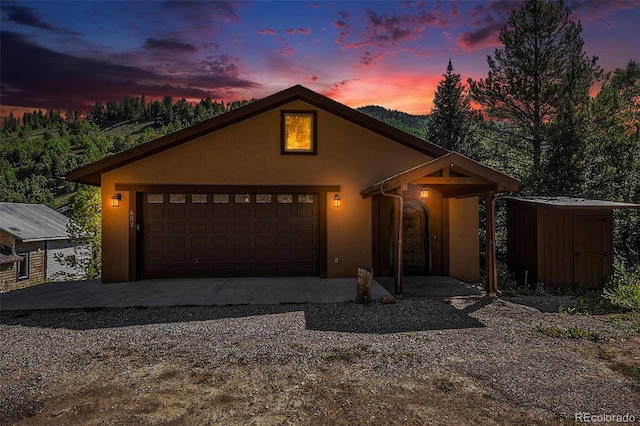 view of front of house with stucco siding, a garage, and driveway