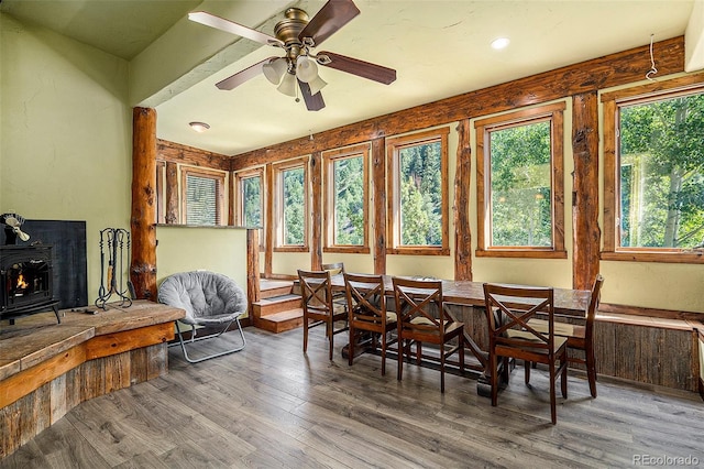 dining area featuring a wood stove, wood finished floors, and ceiling fan