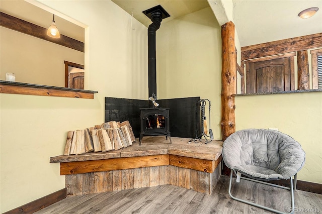 sitting room featuring a wood stove, baseboards, and wood finished floors