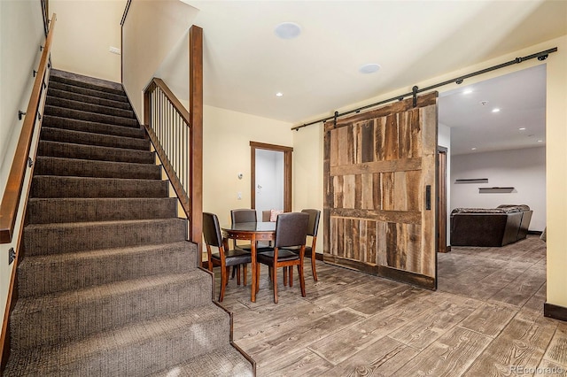 dining area featuring stairs, a barn door, recessed lighting, and wood finished floors