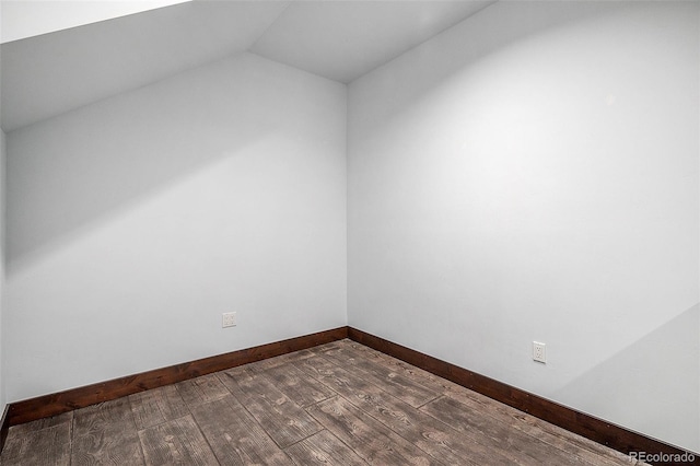 unfurnished room featuring vaulted ceiling, dark wood-style floors, and baseboards