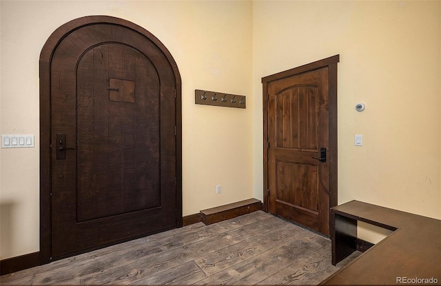 entryway featuring baseboards, arched walkways, and dark wood finished floors