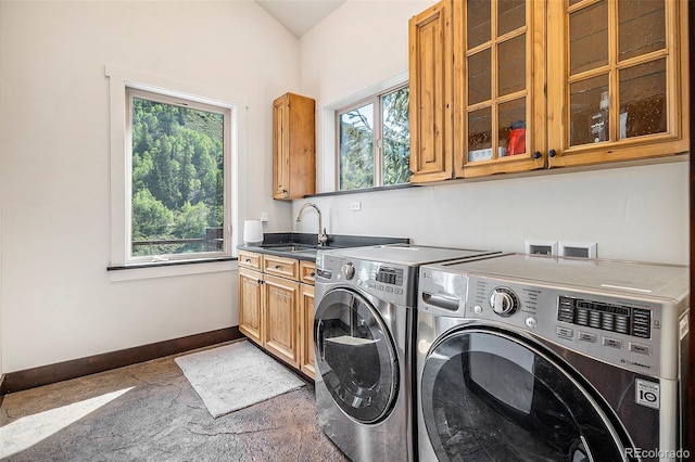 washroom with a sink, baseboards, cabinet space, and washer and clothes dryer