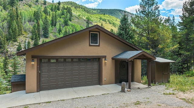 chalet / cabin featuring stucco siding, an outdoor structure, a mountain view, and a wooded view