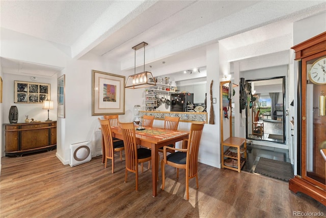 dining area with beamed ceiling, a textured ceiling, and hardwood / wood-style flooring