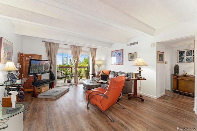 living room featuring beam ceiling, hardwood / wood-style flooring, and a textured ceiling