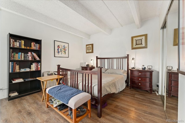 bedroom with a closet, a textured ceiling, beamed ceiling, and wood-type flooring