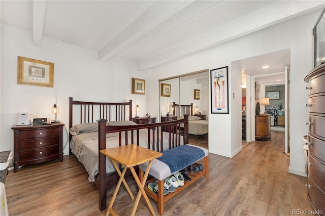 bedroom featuring a closet, a textured ceiling, beamed ceiling, and hardwood / wood-style floors