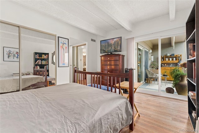 bedroom featuring beamed ceiling, light wood-type flooring, a textured ceiling, and a closet