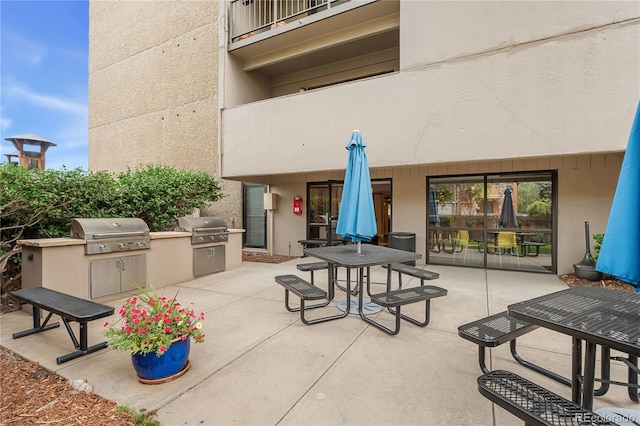 view of patio with grilling area, a balcony, and an outdoor kitchen