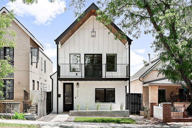 modern inspired farmhouse featuring board and batten siding, fence, a balcony, and a gate