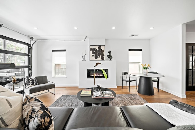 living area with recessed lighting, visible vents, wood finished floors, and a glass covered fireplace