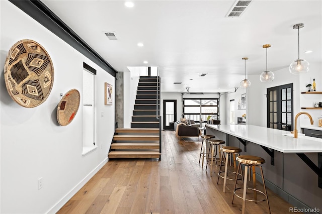 kitchen featuring visible vents, light wood-style floors, a breakfast bar, and french doors