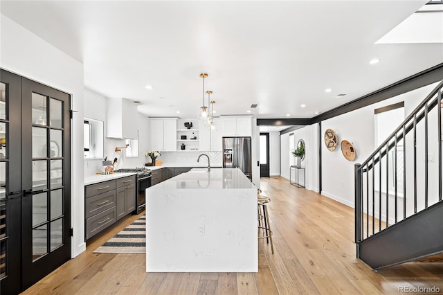 kitchen featuring white cabinetry, stainless steel appliances, light wood-style floors, and open shelves